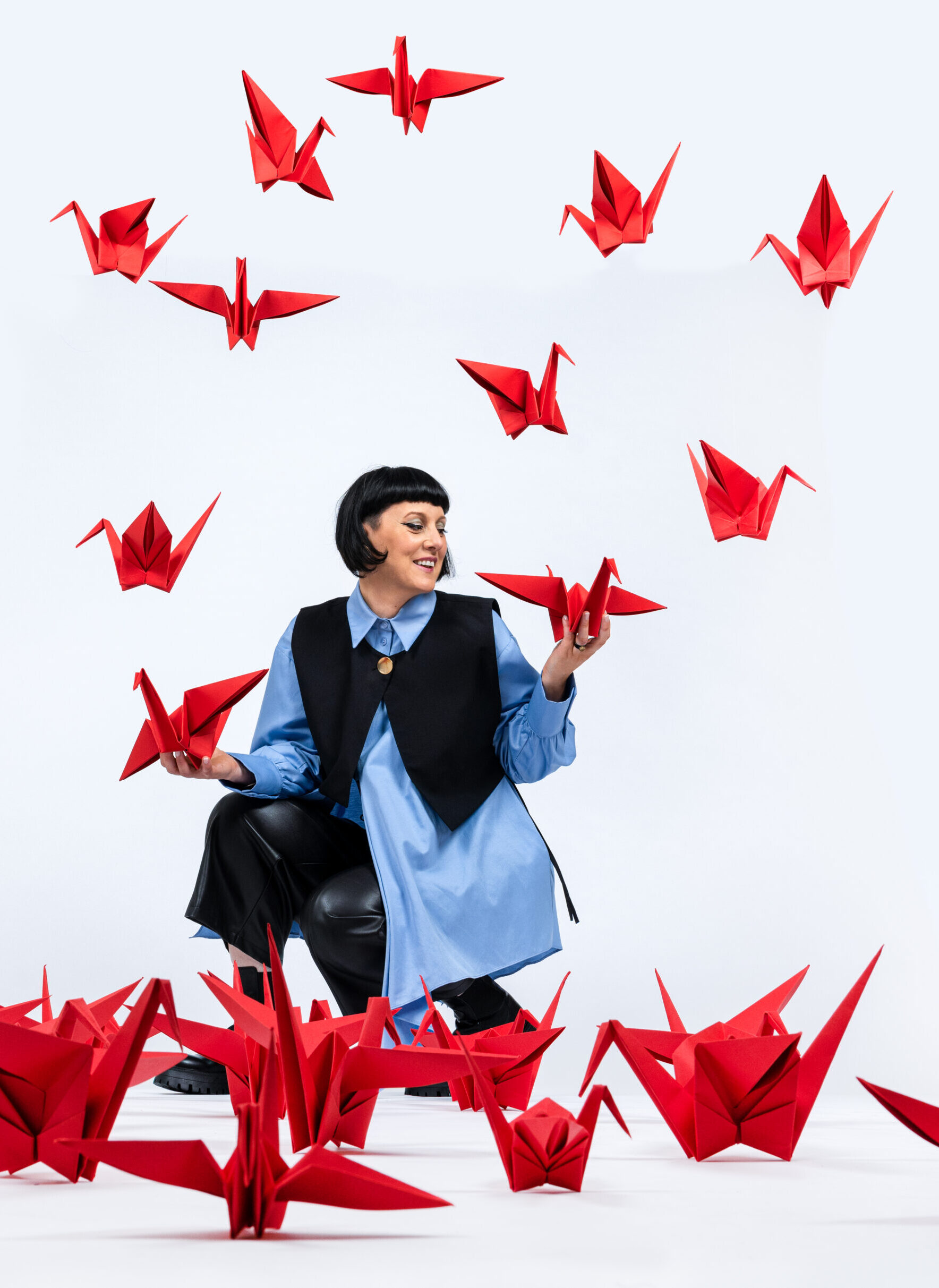 vrouw omringd met rode papieren kraanvogels